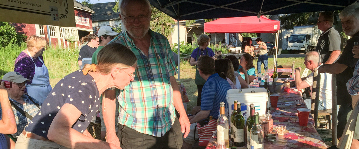 People socializing at an outdoor gathering with drinks on a table.
