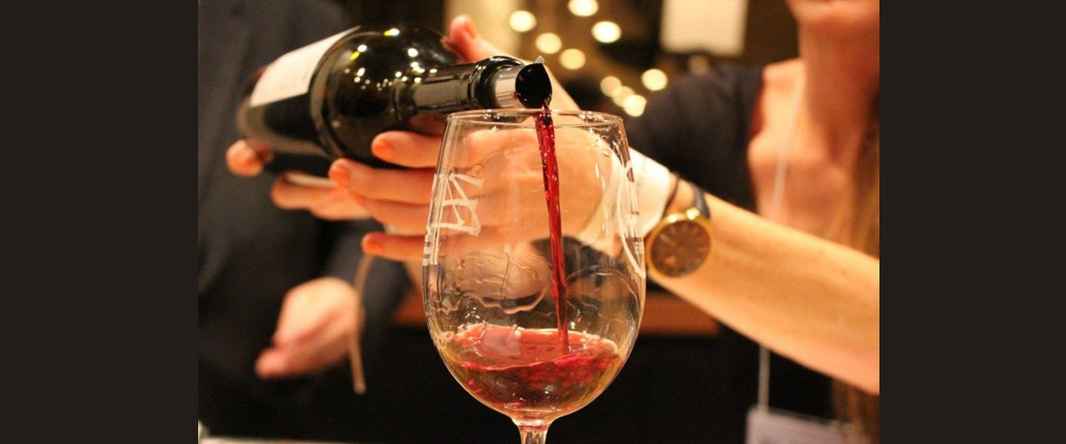 Red wine being poured into a glass in a cozy setting.