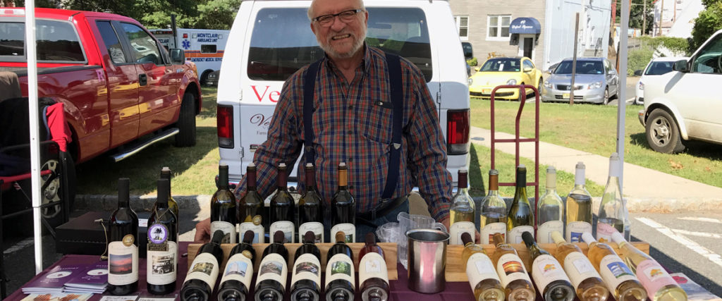 Elderly man selling homemade jams and drinks at an outdoor market stall.