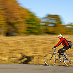 Cyclist riding fast on a countryside road during autumn.